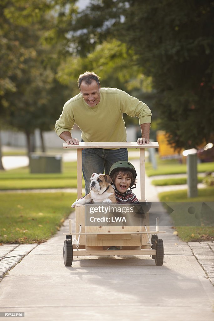 Father Pushing Son and Puppy In Soap Box Car