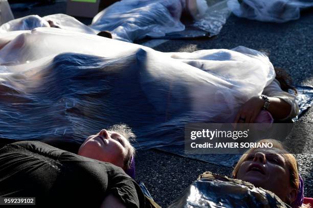 Protesters cover themselves with plastic film as they lie on the street during a demonstration called by the 'Platform 7N Against the Violence...