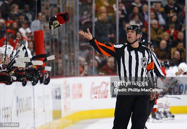 Referee Stephane Auger throws a glove back towards the bench after a fight in a game between the Chicago Blackhawks and the Ottawa Senators at...