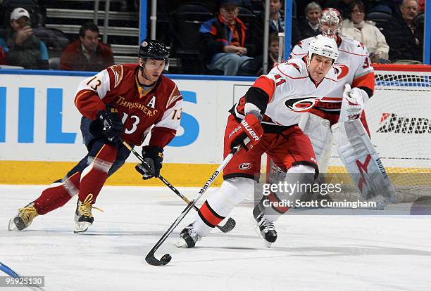 Andrew Alberts of the Carolina Hurricanes carries the puck against Vyacheslav Kozlov of the Atlanta Thrashers at Philips Arena on January 21, 2010 in...