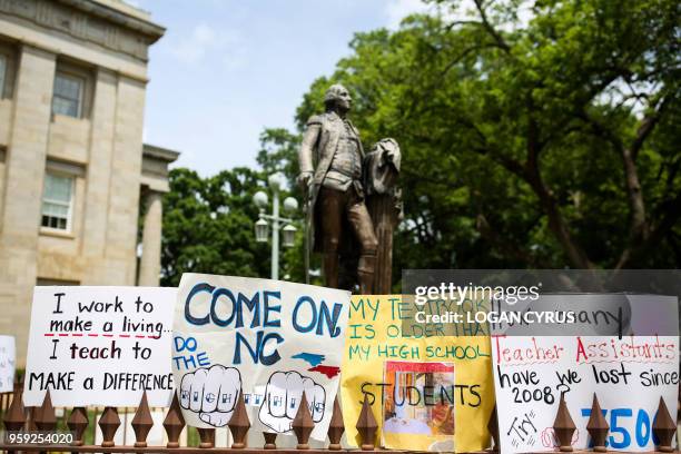 Teachers placed protest signs around a statue of George Washington outside the state capitol building in Raleigh, North Carolina on May, 16 2018. -...