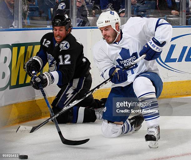 Ian White of the Toronto Maple Leafs clears the puck away from Ryan Malone of the Tampa Bay Lightning during the first period at the St. Pete Times...