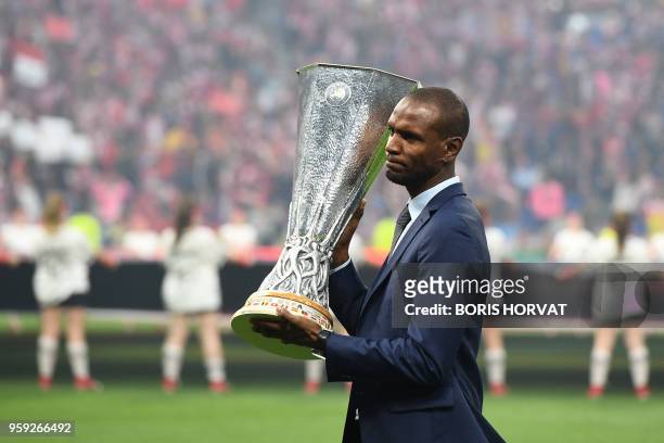 Former French football player Eric Abidal holds the UEFA Europa league trophy as he poses on the pitch prior to the UEFA Europa League final football...