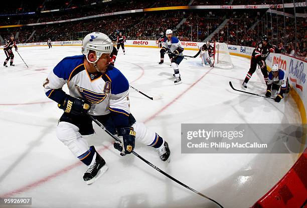 Keith Tkachuk of the St. Louis Blues controls the puck in the corner while teammate David Perron is knocked to the ice by Chris Phillips of the...