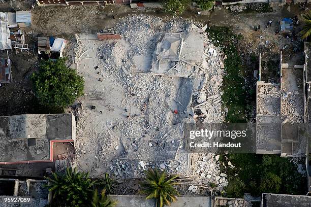 In this handout image provided by the United Nations Stabilization Mission in Haiti , people root through a completely destroyed house 40 kilometers...