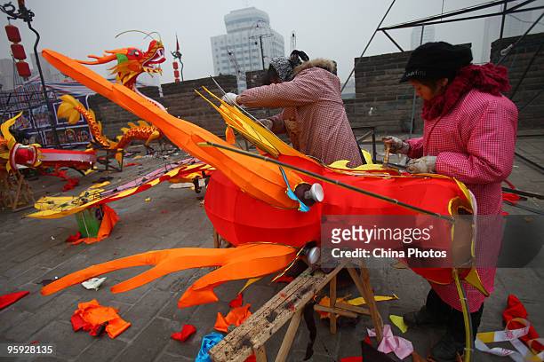 Workers install light decorations for the upcoming Chinese new year at the South Gate of Xian City Wall on January 21, 2010 in Xian of Shaanxi...