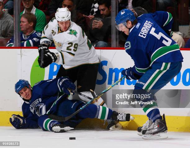 Christian Ehrhoff of the Vancouver Canucks handles the puck up ice after teammate Kyle Wellwood is checked down to the ice by Steve Ott of the Dallas...