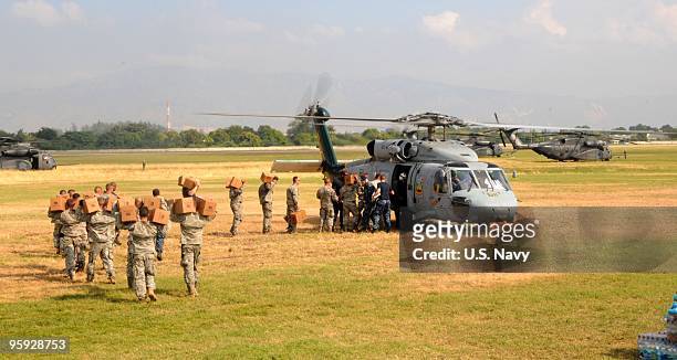 In this handout provided by the U.S. Navy, soldiers load water and humanitarian supplies into an MH-60S Sea Hawk helicopter assigned to the aircraft...