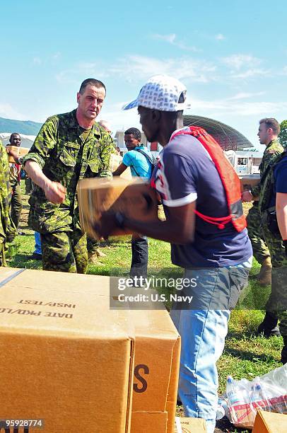 In this handout provided by the U.S. Navy, Canadian soldiers and Haitian civilians unload water and supplies from a CH-53E Sea Dragon helicopter...