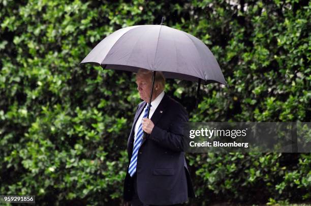 President Donald Trump carries an umbrella while walking towards Marine One to depart from the White House in Washington, D.C., U.S., on Wednesday,...