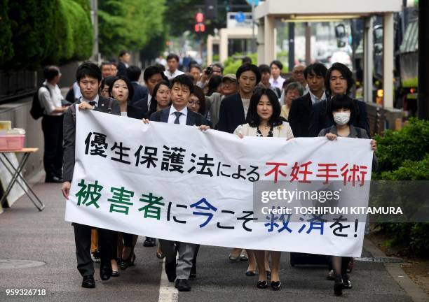 Lawyers and supporters of victims of forced sterilisation under a now-defunct eugenics law, carry a banner saying "Sterilisation under the eugenics...