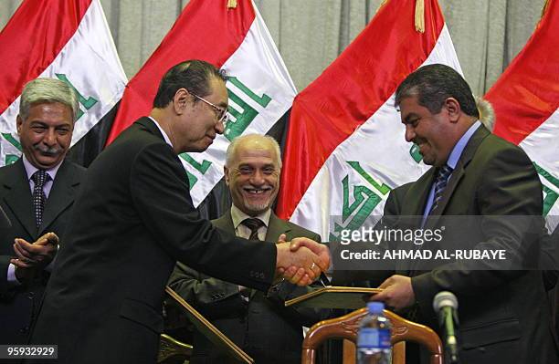 Chairman of Korea Gas, Kangsoo Choo, shakes hands with Ali Muarij, the director of the Misan Oil Company, as Iraqi Oil Minister Hussein Shahristani...