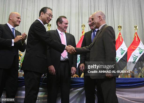 Chairman of Korea Gas Kangsoo Choo, shakes hands with Iraqi Oil Minister Hussein Shahristani as Executive Vice President of USA Occidental Oil and...