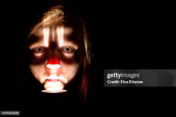 pre-adolescent girl's face, lit by flashlight under her chin - flashlight stockfoto's en -beelden