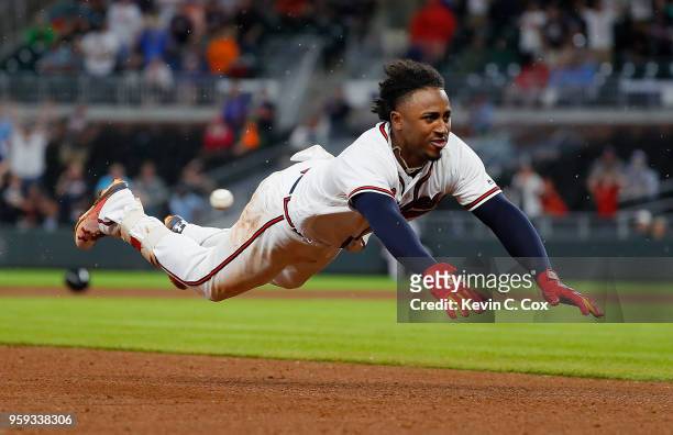 Ozzie Albies of the Atlanta Braves dives safely for third base on his triple hit in the eighth inning against the Chicago Cubs at SunTrust Park on...