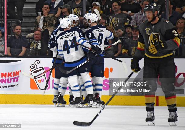 Brayden McNabb of the Vegas Golden Knights skates away as Mark Scheifele of the Winnipeg Jets is congratulated by his teammates after scoring a...