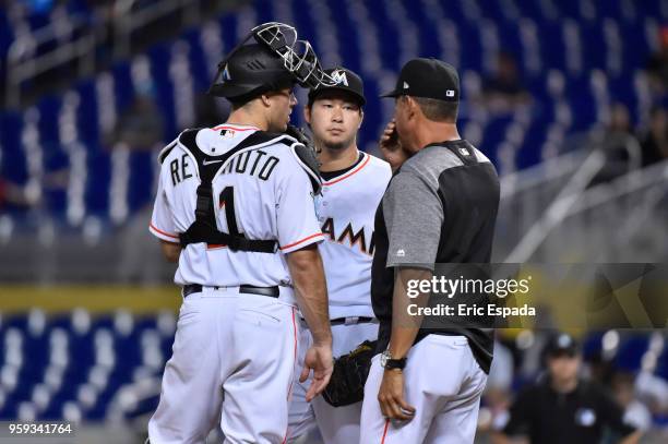 Junichi Tazawa of the Miami Marlins talks to catcher J.T. Realmuto and Pitching Coach Juan Nieves during the sixth inning against the Los Angeles...