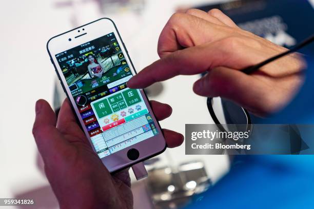 An attendee plays a baccarat game on an Apple Inc. IPhone at the Global Gaming Expo Asia in Macau, China, on Wednesday, May 16, 2018. The expo runs...