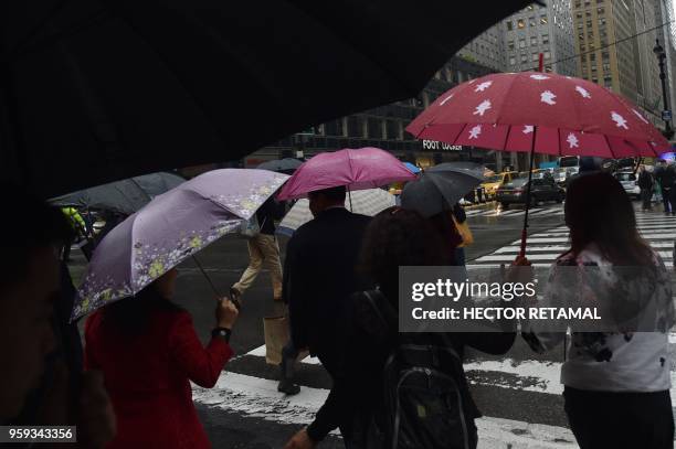 People protect themselves from the rain with umbrellas while walking on 2nd Avenue in New York City on May 16, 2018.