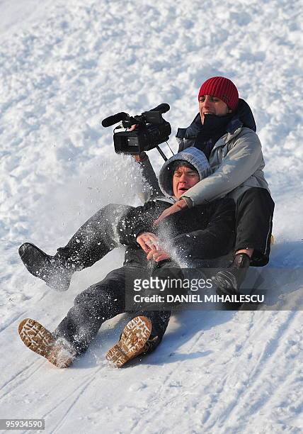 People enjoy sliding on a piece of plastic bag in Parcul Tineretului park in Bucharest on January 22, 2010. AFP PHOTO DANIEL MIHAILESCU