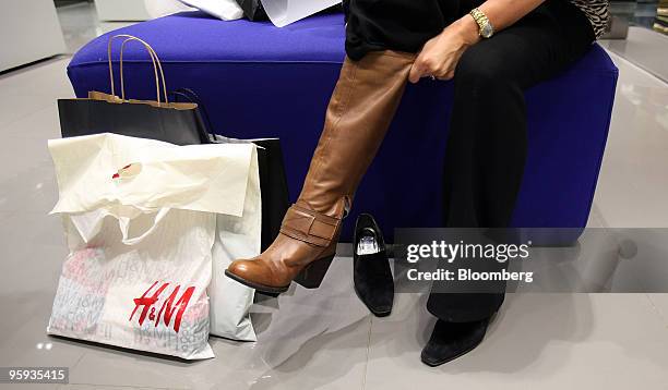 Woman tries a pair of boots on at a shoe store in the Bluewater Shopping & Leisure Centre near Greenhithe, U.K., on Thursday, Jan. 21, 2010. U.K....