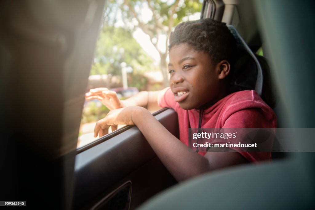 Ragazzo afro-americano sul sedile posteriore di un'auto.