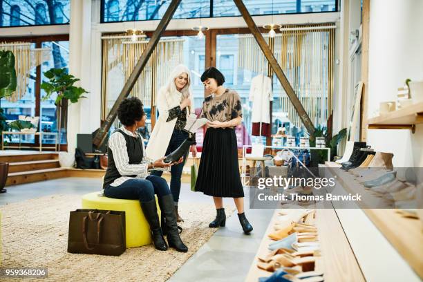 clothing boutique owner showing clients details on boots while shopping for shoes - older women in short skirts stock pictures, royalty-free photos & images