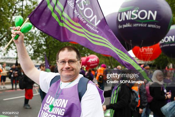 Man carries a flag of the UNISON trade union as demonstrators calling for fairer pay and rights for workers, as well as against public service cuts...