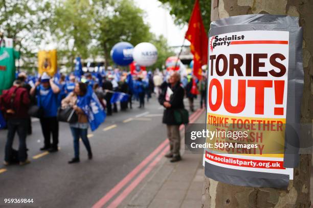 Tories Out' placard stands fixed to a tree as demonstrators calling for fairer pay and rights for workers, as well as against public service cuts and...