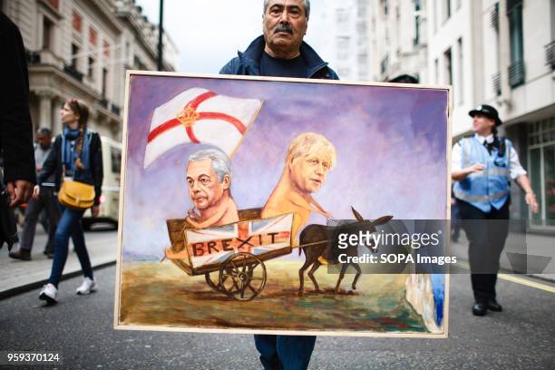 Political artist Kaya Mar carries a painting of "Brexit" advocates Nigel Farage and Boris Johnson being led off a cliff by a blindfolded donkey...