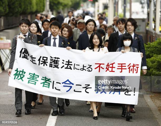 Lawyers and other people representing a Japanese man seeking damages from the Japanese government march to the Tokyo District Court on May 17 to file...