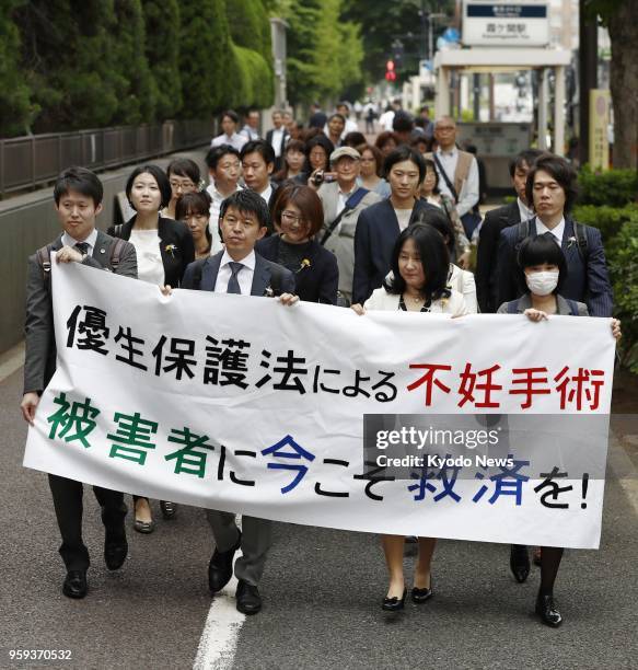 Lawyers and other people representing a Japanese man seeking damages from the Japanese government march to the Tokyo District Court on May 17 to file...