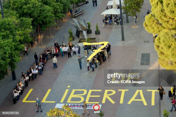 An aerial view of the demonstration with protesters forming a '7' with yellow placards. Around fifty people gathered in L'Hospitalet City to demand...