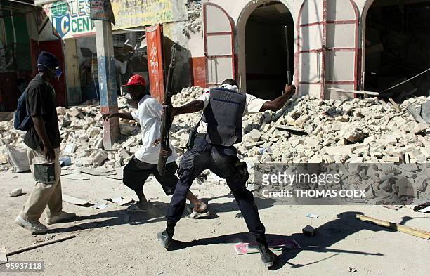 Haitian policeman chases looters with a baton on January 21, 2010 in Port-au-Prince, Haiti. Not knowing where to turn, many residents have taken to...