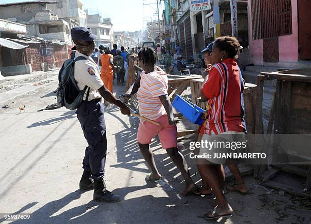 Haitian policeman chases looters with a baton on January 21, 2010 in Port-au-Prince, Haiti. Not knowing where to turn, many residents have taken to...