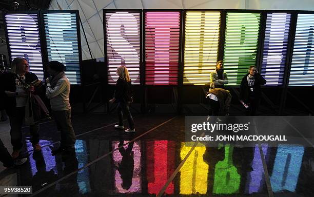 Visitors walk past a giant neon sign reading "Be stupid" in front of the stand of Italian clothing design company Diesel at the Bread and Butter...