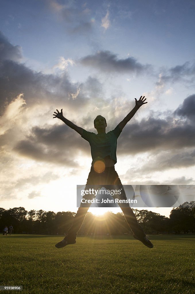 Silhouette of couple running and jumping at sunset