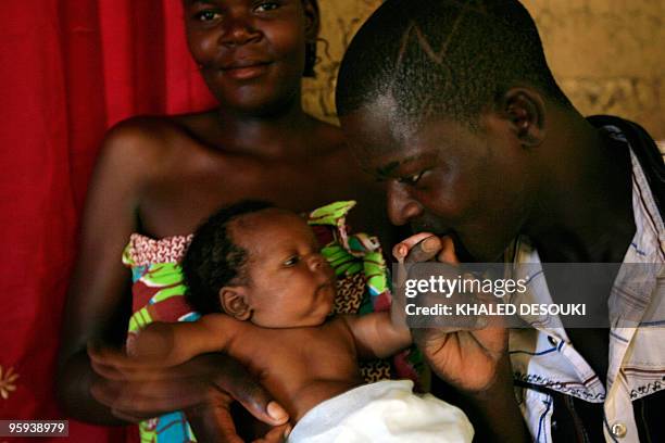 Angolan singer Paulo Joaquim Maria 22, kisses his one-month baby Didinho as his wife Candida Tchilombo 20, looks on at their house in Mina village 15...