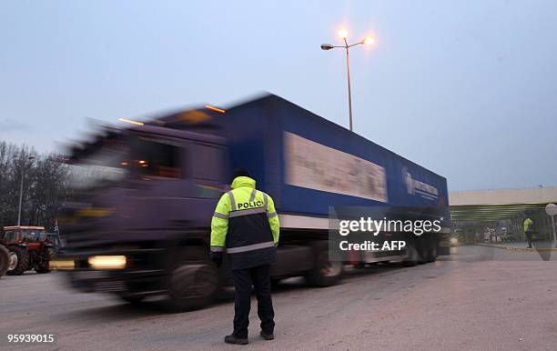 Policeman looks at passing trucks after protesting Greek farmers unblocked the Greek Bulgarian boarders in Promachonas on January 22, 2010. Bulgarian...