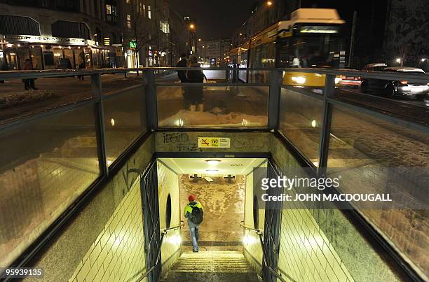 Man walks into the U6 underground station at the Oranienburger Tor station, as a tram arrives in Berlin January 13, 2010. AFP PHOTO / JOHN MACDOUGALL