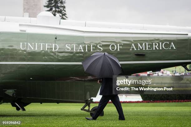 President Donald J. Trump, with an umbrella, walks from the Oval Office to the Marine One helicopter as he departs heading to Walter Reed National...