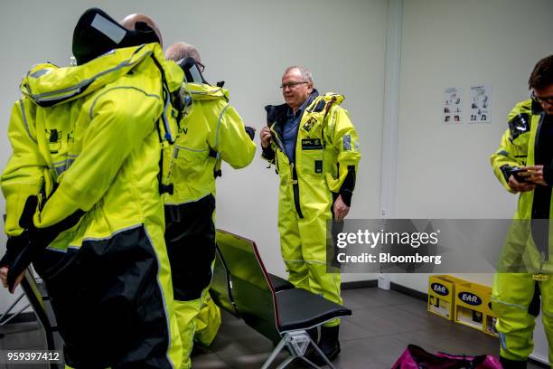 Eldar Saetre, chief executive officer of Equinor ASA, center, dresses in protective overalls before boarding a helicopter on route to the Troll A...