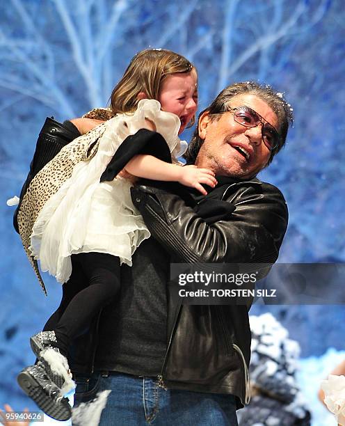 Italian designer Roberto Cavalli carries a crying young girl on the catwalk at the end of his fashion show for the labels "Roberto Cavalli Angels"...