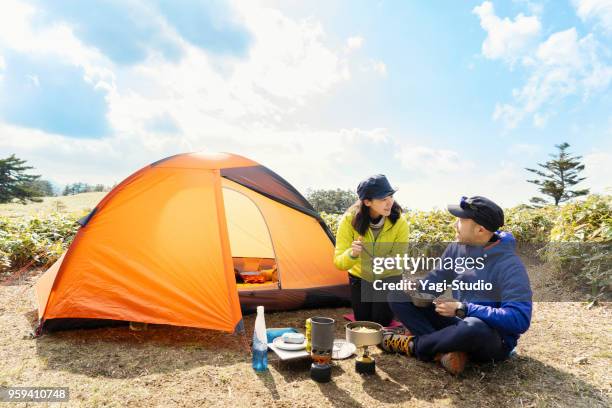 男性と女性は自然の中のキャンプでアウトドア クッキングを楽しむ - tent ストックフォトと画像