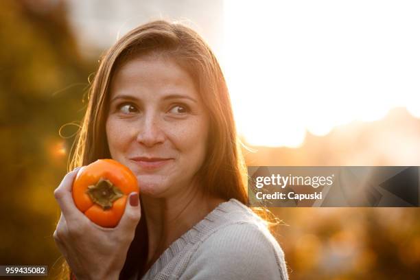mulher comendo caqui - caqui fruta tropical - fotografias e filmes do acervo