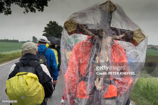 Pilgrim carries a cross covered with a plastic shield to protect it against the rain as he takes part in a pilgrimage on foot on a 111km long tour...
