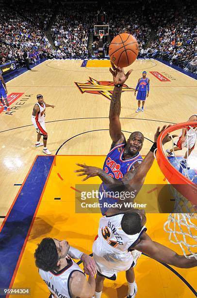 Shaquille O'Neal of the Cleveland Cavaliers shoots over Chris Hunter and Vladimir Radmanovic of the Golden State Warriors during the game at Oracle...