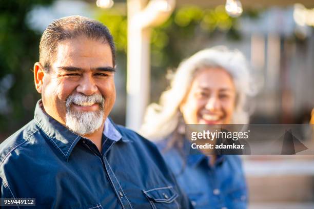 senior mexican man smiling with wife in the background - fat guy stock pictures, royalty-free photos & images