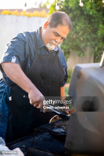 senior mexican man grilling steaks at bbq - fat mexican man stock pictures, royalty-free photos & images