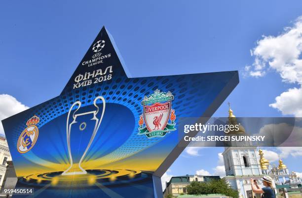 Woman takes a picture as she walks past a star shaped billboard announcing the 2018 UEFA Champions League Final in the city centre of Kiev on May 17...
